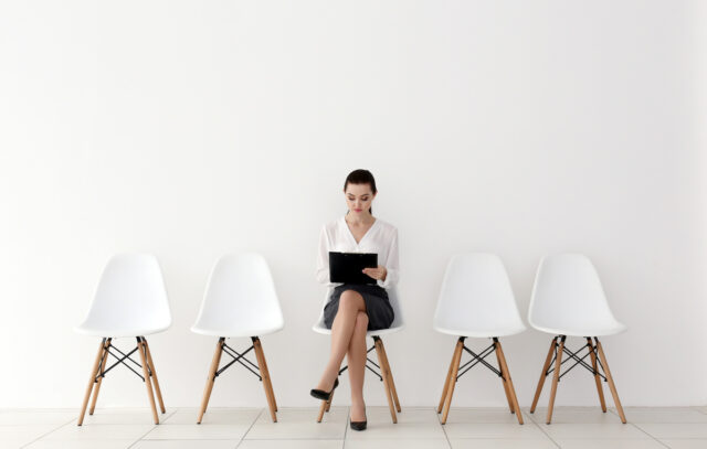 Mujer a la espera de entrevista de trabajo, sentada en el centro de la imagen