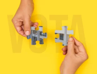 Hände halten Puzzleteile mit einem Teil der ESI-Fassade. Hinter dem Wort ABSTIMMUNG
