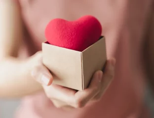 Woman holding a cardboard box on which there is a red heart