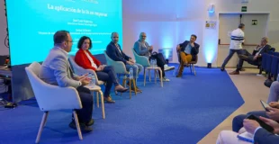 Personas sentadas participando en una mesa redonda en el salón de actos Alan Turing de la ESI