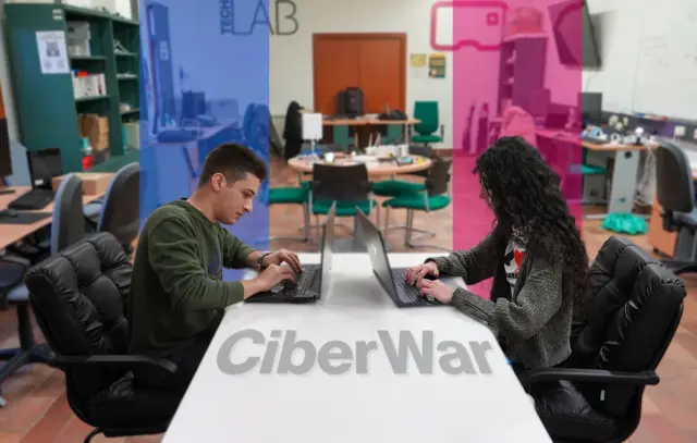 dos estudiantes en el laboratorio enfrentados a través de un computador