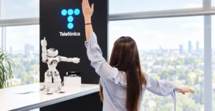 Mujer frente a robot y logo de telefónica