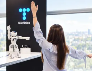 Mujer frente a robot y logo de telefónica