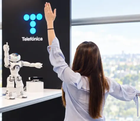 Mujer frente a robot y logo de telefónica