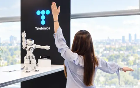 Mujer frente a robot y logo de telefónica