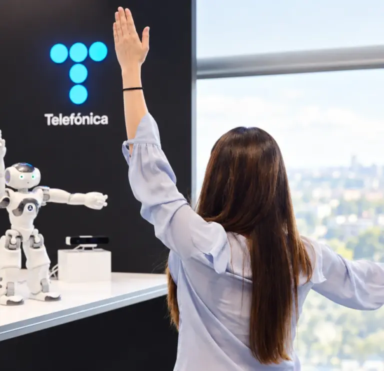 Mujer frente a robot y logo de telefónica