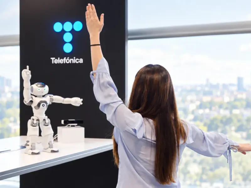 Mujer frente a robot y logo de telefónica
