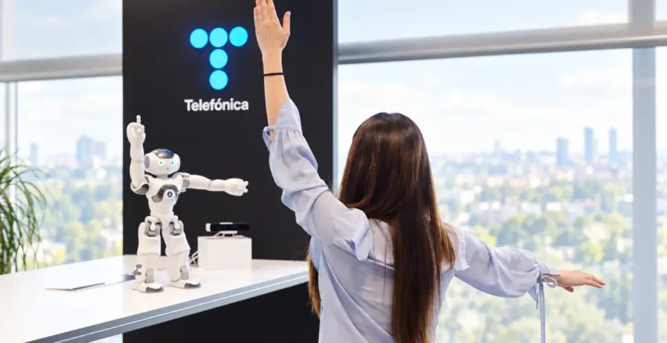 Mujer frente a robot y logo de telefónica